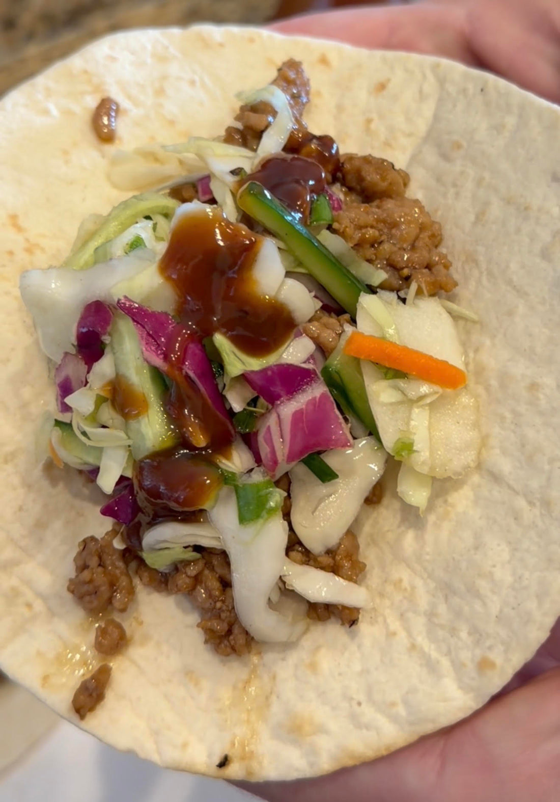 Ground pork taco with cucumber cabbage slaw and Asian Bang Sauce in a flour tortilla