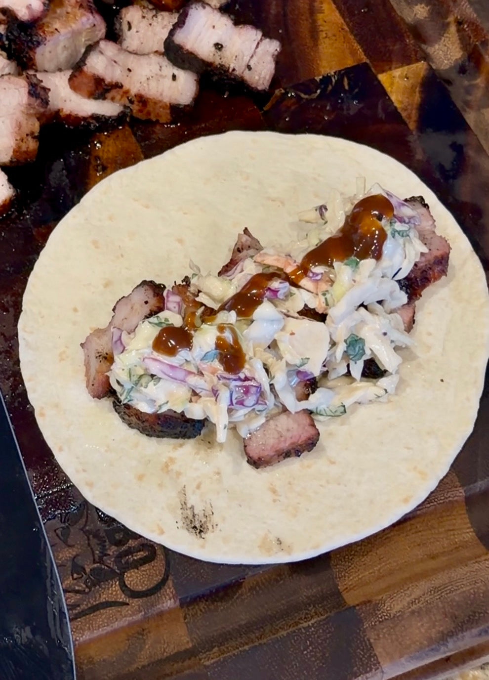 Filipino-style grilled pork belly taco topped with creamy Asian Bang Slaw, cilantro, and Asian Bang Sauce on a flour tortilla.